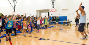 John Walters, right, a physiologist with the Health and Wellness Center, leads children in jumping jacks prior to participating in the Child