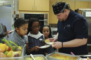 Local Chef LJ Klink serves children Mediterranean Frittata made by the kids during a cooking class at Joint Base Lewis-McChord, Wash., March