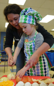 Kim Raymond, an Army spouse, helps her daughter Mackenzie to cut an onion during a cooking class at Joint Base Lewis-McChord, Wash., March 2